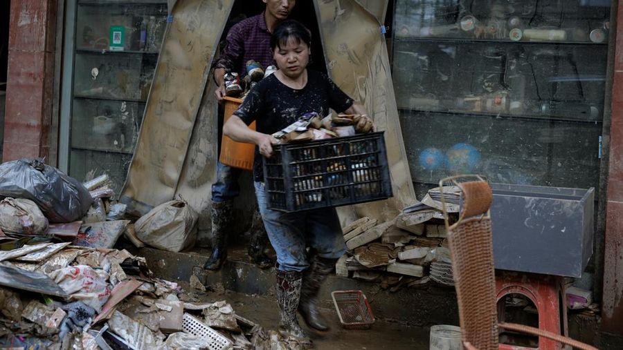 Sebuah mobil dan tumpukan puing-puing terlihat di jalan setelah banjir menyusul hujan lebat di daerah Pingjiang, Yueyang, provinsi Hunan, Tiongkok 3 Juli 2024. (REUTERS/Tingshu Wang)