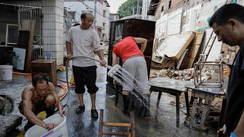 Sebuah mobil dan tumpukan puing-puing terlihat di jalan setelah banjir menyusul hujan lebat di daerah Pingjiang, Yueyang, provinsi Hunan, Tiongkok 3 Juli 2024. (REUTERS/Tingshu Wang)