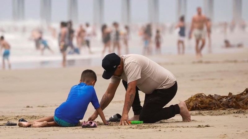 Orang-orang menikmati pantai pada liburan Hari Kemerdekaan Empat Juli saat cuaca panas di Huntington Beach, California, AS 4 Juli 2024. (REUTERS/Etienne Laurent)
