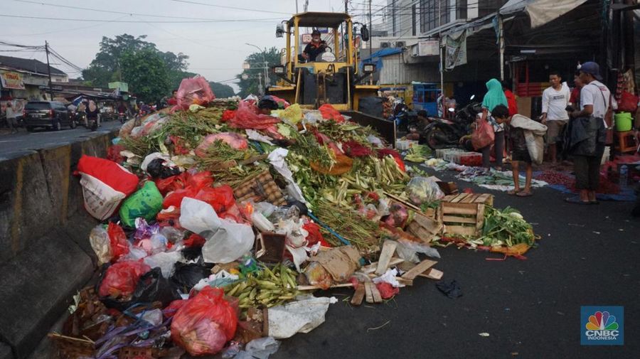 Seorang anak melintas di samping alat berat saat penanganan tumpukan sampah organik dan sisa makanan di kawasan Pasar Minggu, Jakarta, Jumat, (5/7/2024). (CNBC Indonesia/Muhammad Sabki)