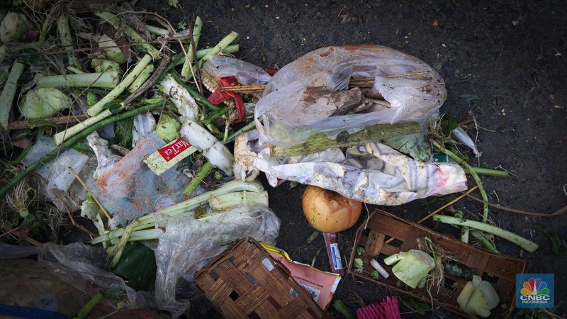 Seorang anak melintas di samping alat berat saat penanganan tumpukan sampah organik dan sisa makanan di kawasan Pasar Minggu, Jakarta, Jumat, (5/7/2024). (CNBC Indonesia/Muhammad Sabki)
