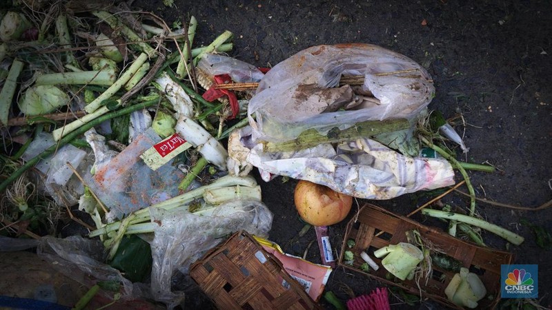 Seorang anak melintas di samping alat berat saat penanganan tumpukan sampah organik dan sisa makanan di kawasan Pasar Minggu, Jakarta, Jumat, (5/7/2024). (CNBC Indonesia/Muhammad Sabki)