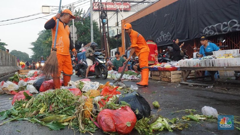 Seorang anak melintas di samping alat berat saat penanganan tumpukan sampah organik dan sisa makanan di kawasan Pasar Minggu, Jakarta, Jumat, (5/7/2024). (CNBC Indonesia/Muhammad Sabki)