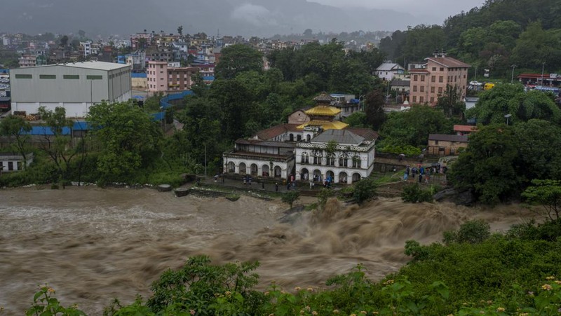 Masyarakat menyaksikan banjirnya sungai Bagmati di Kathmandu, Nepal, Sabtu, 6 Juli 2024. (AP Photo/Niranjan Shrestha)