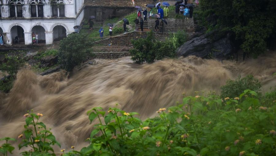 Masyarakat menyaksikan banjirnya sungai Bagmati di Kathmandu, Nepal, Sabtu, 6 Juli 2024. (AP Photo/Niranjan Shrestha)