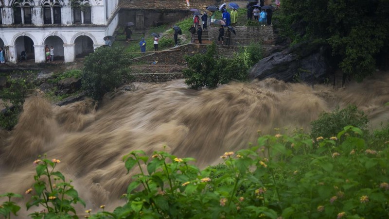 Masyarakat menyaksikan banjirnya sungai Bagmati di Kathmandu, Nepal, Sabtu, 6 Juli 2024. (AP Photo/Niranjan Shrestha)
