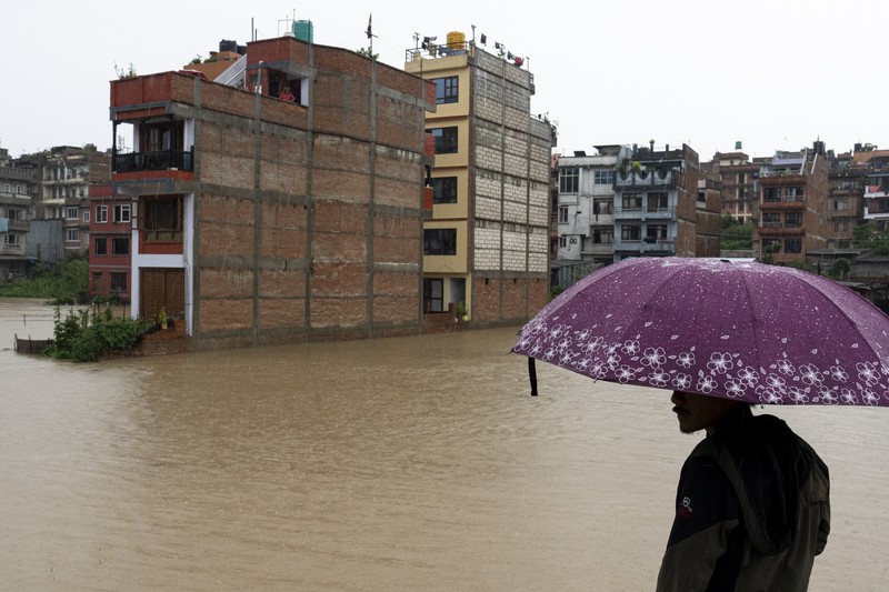 Masyarakat menyaksikan banjirnya sungai Bagmati di Kathmandu, Nepal, Sabtu, 6 Juli 2024. (AP Photo/Niranjan Shrestha)