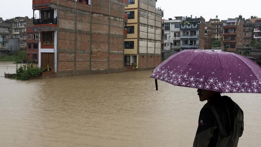 Masyarakat menyaksikan banjirnya sungai Bagmati di Kathmandu, Nepal, Sabtu, 6 Juli 2024. (AP Photo/Niranjan Shrestha)