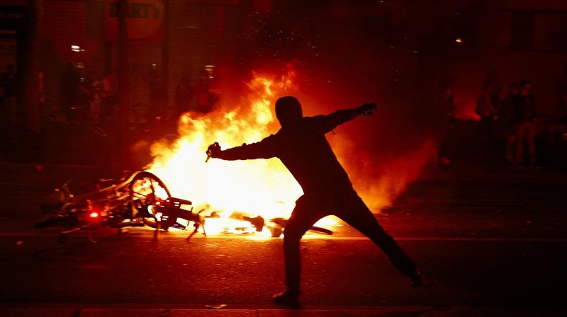 Seorang pengunjuk rasa melemparkan molotov saat bentrokan dengan polisi menyusul hasil parsial pada putaran kedua pemilihan awal parlemen Prancis, di Place de la Republique di Paris, Prancis, Minggu (7/7/2024). (REUTERS/Yara Nardi)