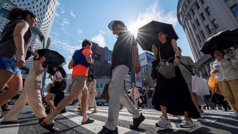 Pejalan kaki berjalan di persimpangan di pusat kota Tokyo yang suhunya mencapai 35 derajat Celcius pada 8 Juli 2024. (Photo by Kazuhiro NOGI / AFP)