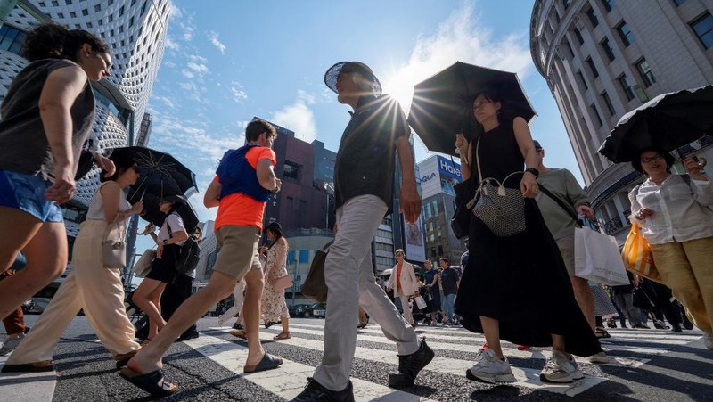 Orang-orang yang memegang payung duduk di bangku di bawah terik matahari di sebuah taman di Tokyo, Senin, 8 Juli 2024. Cuaca panas pada hari Senin telah terjadi dengan suhu meningkat lebih dari 35 derajat Celcius (95 derajat Fahrenheit) di Tokyo, menurut Jepang Badan Meteorologi. (AP Photo/Eugene Hoshiko)