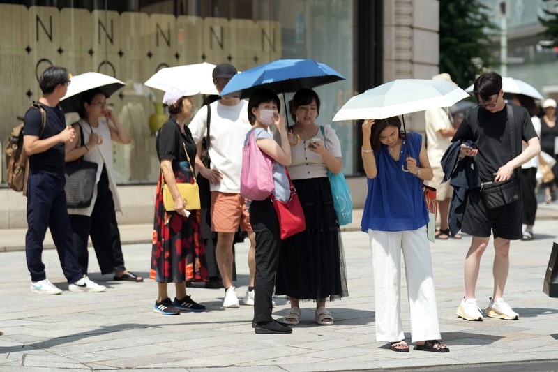 Orang-orang yang memegang payung duduk di bangku di bawah terik matahari di sebuah taman di Tokyo, Senin, 8 Juli 2024. Cuaca panas pada hari Senin telah terjadi dengan suhu meningkat lebih dari 35 derajat Celcius (95 derajat Fahrenheit) di Tokyo, menurut Jepang Badan Meteorologi. (AP Photo/Eugene Hoshiko)