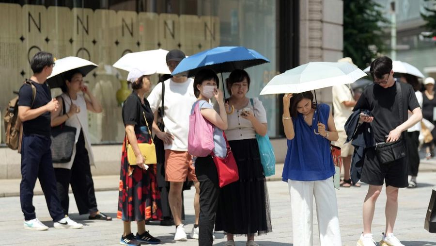 Orang-orang yang memegang payung duduk di bangku di bawah terik matahari di sebuah taman di Tokyo, Senin, 8 Juli 2024. Cuaca panas pada hari Senin telah terjadi dengan suhu meningkat lebih dari 35 derajat Celcius (95 derajat Fahrenheit) di Tokyo, menurut Jepang Badan Meteorologi. (AP Photo/Eugene Hoshiko)