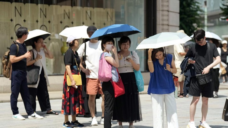 Orang-orang yang memegang payung duduk di bangku di bawah terik matahari di sebuah taman di Tokyo, Senin, 8 Juli 2024. Cuaca panas pada hari Senin telah terjadi dengan suhu meningkat lebih dari 35 derajat Celcius (95 derajat Fahrenheit) di Tokyo, menurut Jepang Badan Meteorologi. (AP Photo/Eugene Hoshiko)