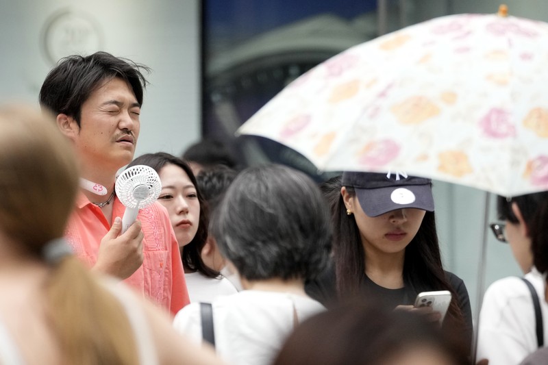 Orang-orang yang memegang payung duduk di bangku di bawah terik matahari di sebuah taman di Tokyo, Senin, 8 Juli 2024. Cuaca panas pada hari Senin telah terjadi dengan suhu meningkat lebih dari 35 derajat Celcius (95 derajat Fahrenheit) di Tokyo, menurut Jepang Badan Meteorologi. (AP Photo/Eugene Hoshiko)