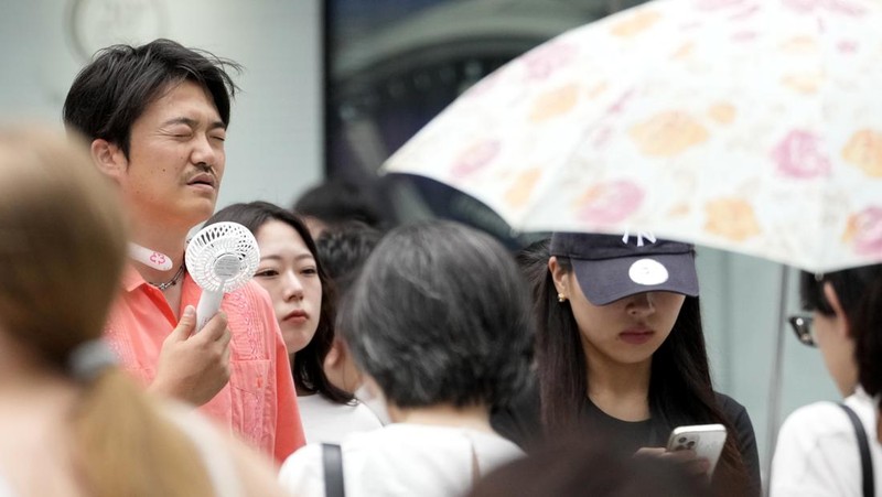 Orang-orang yang memegang payung duduk di bangku di bawah terik matahari di sebuah taman di Tokyo, Senin, 8 Juli 2024. Cuaca panas pada hari Senin telah terjadi dengan suhu meningkat lebih dari 35 derajat Celcius (95 derajat Fahrenheit) di Tokyo, menurut Jepang Badan Meteorologi. (AP Photo/Eugene Hoshiko)