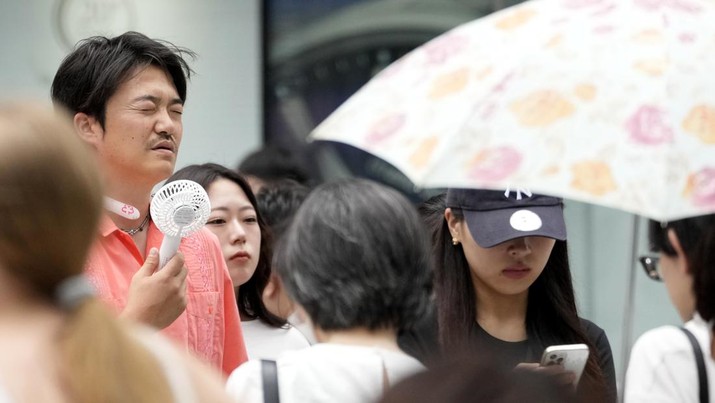 Seorang pejalan kaki menggunakan kipas angin listrik portabel di distrik perbelanjaan Ginza yang terkenal di Tokyo, Jepang, Kamis, 4 Juli 2024. Suhu di Tokyo naik lebih dari 30 derajat Celcius (86 derajat Fahrenheit), menurut biro meteorologi Jepang pada hari Rabu. (AP Photo/Shuji Kajiyama)