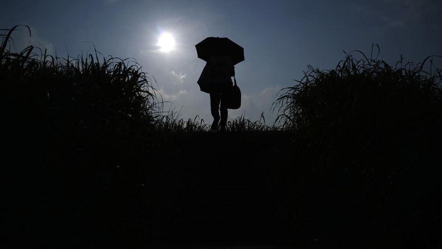 Orang-orang yang memegang payung duduk di bangku di bawah terik matahari di sebuah taman di Tokyo, Senin, 8 Juli 2024. Cuaca panas pada hari Senin telah terjadi dengan suhu meningkat lebih dari 35 derajat Celcius (95 derajat Fahrenheit) di Tokyo, menurut Jepang Badan Meteorologi. (AP Photo/Eugene Hoshiko)