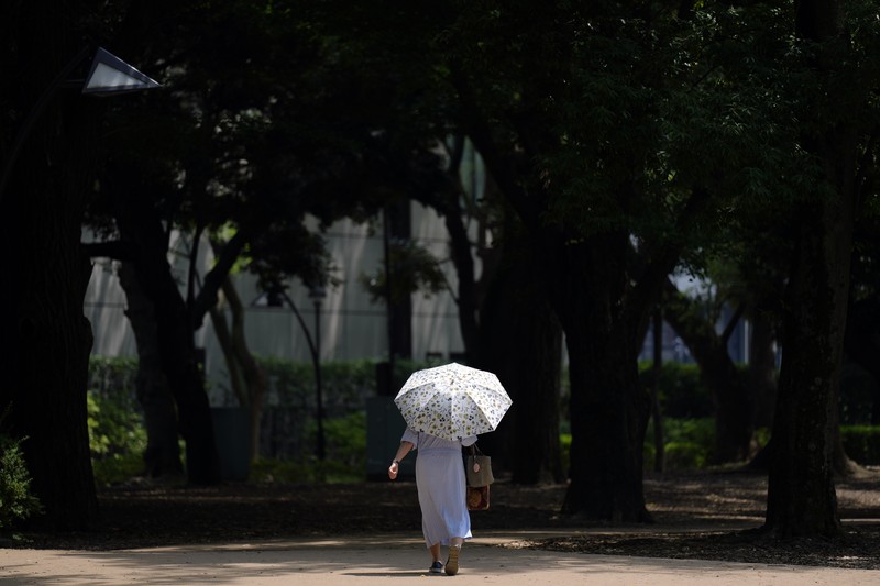 Orang-orang yang memegang payung duduk di bangku di bawah terik matahari di sebuah taman di Tokyo, Senin, 8 Juli 2024. Cuaca panas pada hari Senin telah terjadi dengan suhu meningkat lebih dari 35 derajat Celcius (95 derajat Fahrenheit) di Tokyo, menurut Jepang Badan Meteorologi. (AP Photo/Eugene Hoshiko)