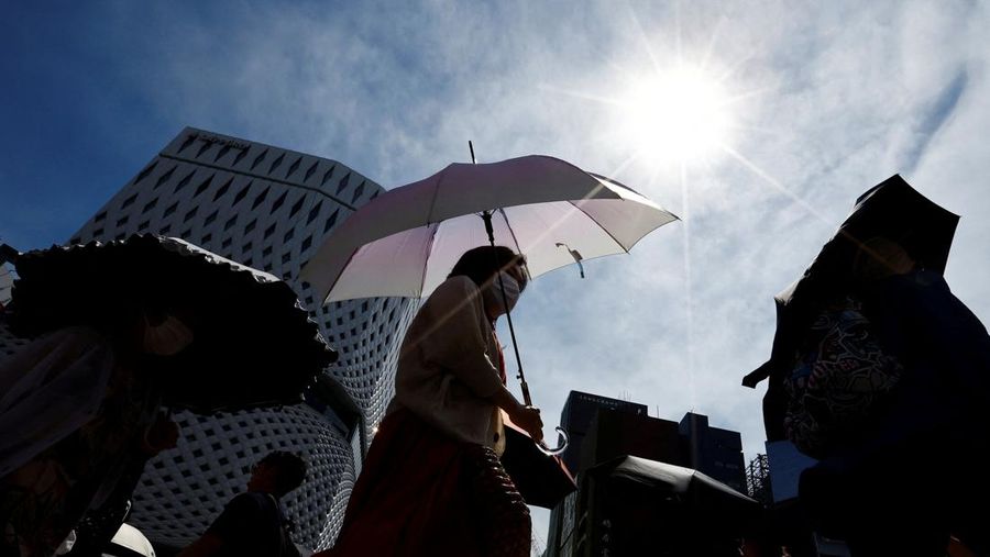 Pejalan kaki yang memegang payung berjalan di bawah sinar matahari di jalan ketika pemerintah Jepang mengeluarkan peringatan sengatan panas di Tokyo dan prefektur lainnya, di Tokyo, Jepang pada 9 Juli 2024. (REUTERS/Issei Kato)