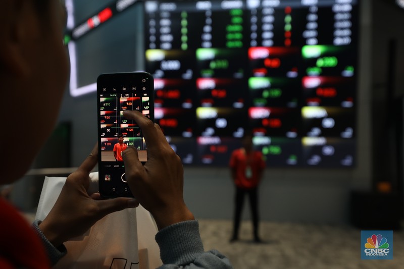 Karyawan berdiri dengan latar belakang layar digital pergerakan Indeks Harga Saham Gabungan (IHSG) di Bursa Efek Indonesia, Jakarta, Kamis (11/7/2024). Karyawan berdiri dengan latar belakang layar digital pergerakan Indeks Harga Saham Gabungan (IHSG) di Bursa Efek Indonesia, Jakarta, Kamis (11/7/2024). (CNBC Indonesia/Tri Susilo)