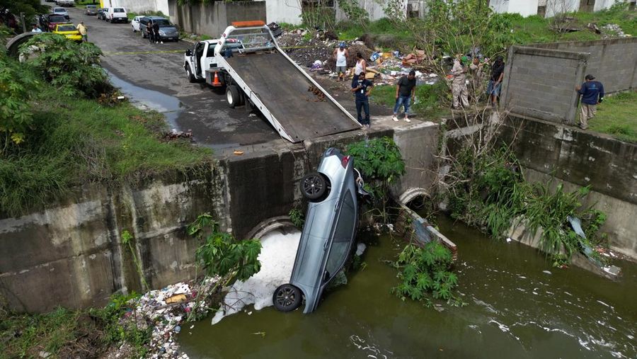 Pria mendorong mobil di jalan yang banjir saat hujan lebat di Veracruz, Meksiko 9 Juli 2024. (REUTERS/Stringer)