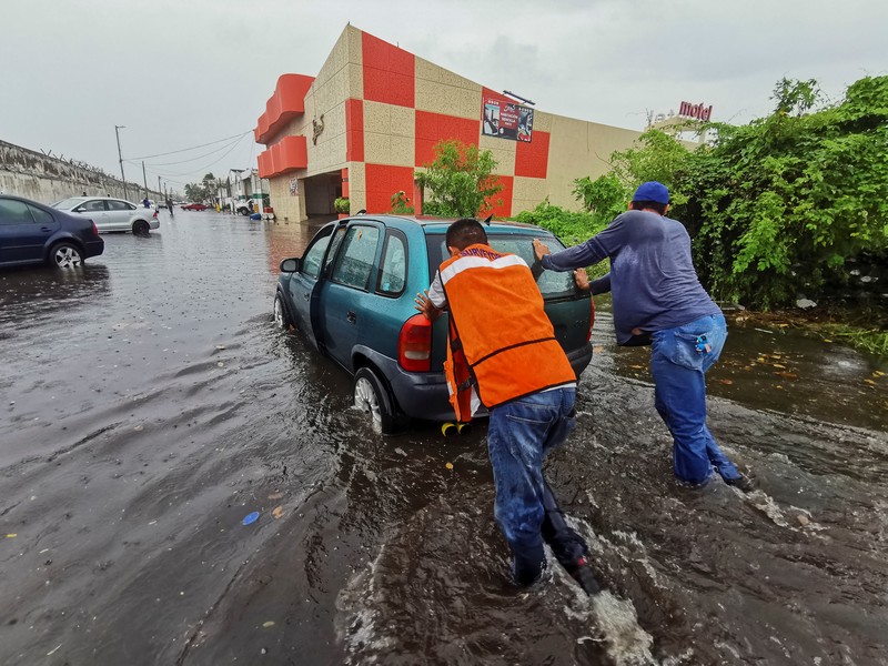 Pria mendorong mobil di jalan yang banjir saat hujan lebat di Veracruz, Meksiko 9 Juli 2024. Pria mendorong mobil di jalan yang banjir saat hujan lebat di Veracruz, Meksiko 9 Juli 2024. (REUTERS/Stringer)