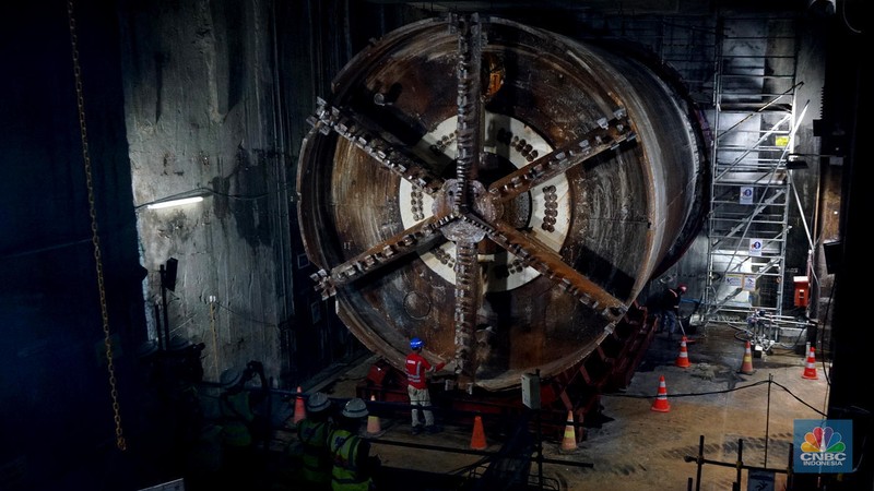 Sejumlah pekerja melintas di samping Tunnel Boring Machine (TBM) atau mesin bor bawah tanah di proyek MRT fase 2A Bundaran HI-Kota di kawasan Glodok, Jakarta, Kamis (11/7/2024). (CNBC Indonesia/Muhammad Sabki)