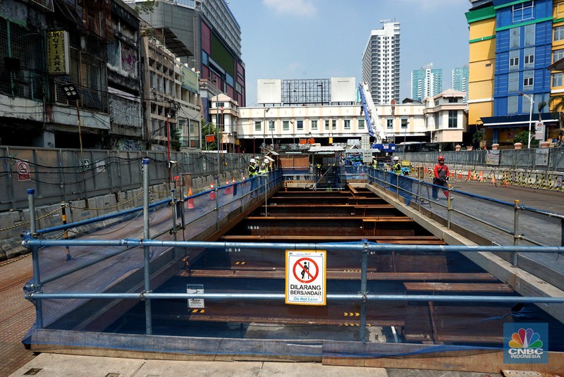 Sejumlah pekerja melintas di samping Tunnel Boring Machine (TBM) atau mesin bor bawah tanah di proyek MRT fase 2A Bundaran HI-Kota di kawasan Glodok, Jakarta, Kamis (11/7/2024). (CNBC Indonesia/Muhammad Sabki)