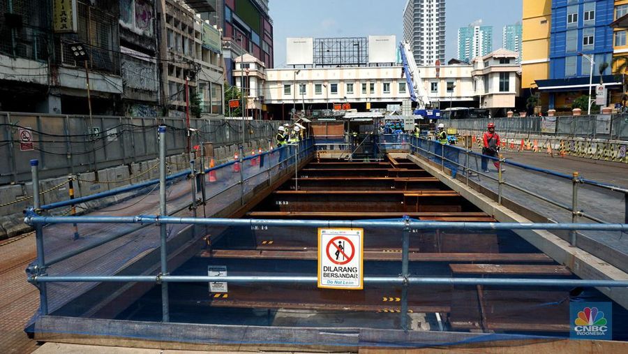 Sejumlah pekerja melintas di samping Tunnel Boring Machine (TBM) atau mesin bor bawah tanah di proyek MRT fase 2A Bundaran HI-Kota di kawasan Glodok, Jakarta, Kamis (11/7/2024). (CNBC Indonesia/Muhammad Sabki)
