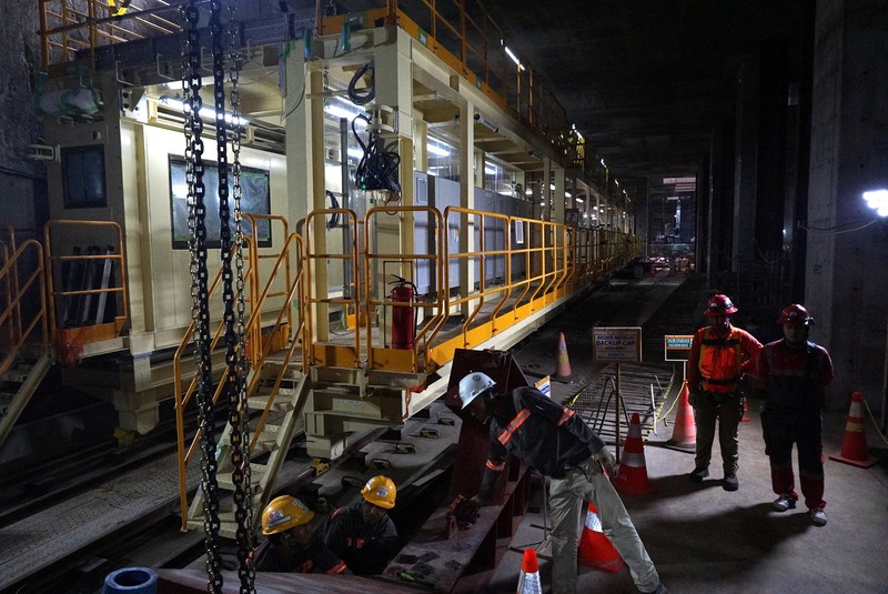 Sejumlah pekerja melintas di samping Tunnel Boring Machine (TBM) atau mesin bor bawah tanah di proyek MRT fase 2A Bundaran HI-Kota di kawasan Glodok, Jakarta, Kamis (11/7/2024). (CNBC Indonesia/Muhammad Sabki)