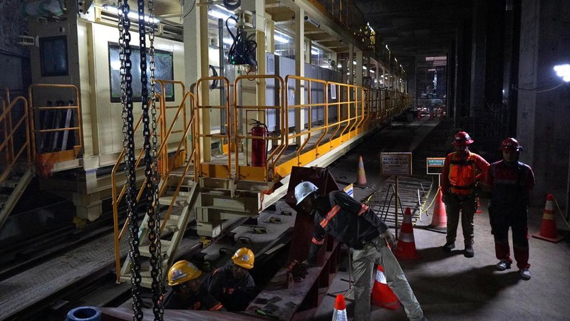 Sejumlah pekerja melintas di samping Tunnel Boring Machine (TBM) atau mesin bor bawah tanah di proyek MRT fase 2A Bundaran HI-Kota di kawasan Glodok, Jakarta, Kamis (11/7/2024). (CNBC Indonesia/Muhammad Sabki)