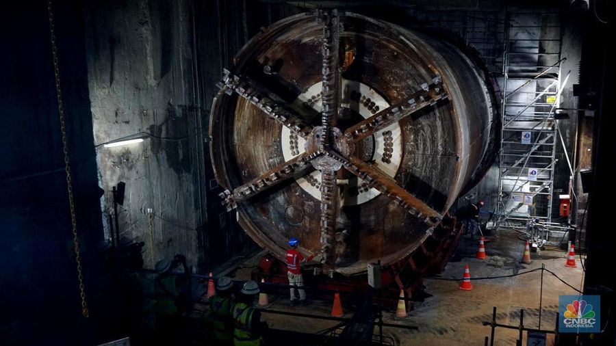 Sejumlah pekerja melintas di samping Tunnel Boring Machine (TBM) atau mesin bor bawah tanah di proyek MRT fase 2A Bundaran HI-Kota di kawasan Glodok, Jakarta, Kamis (11/7/2024). (CNBC Indonesia/Muhammad Sabki)