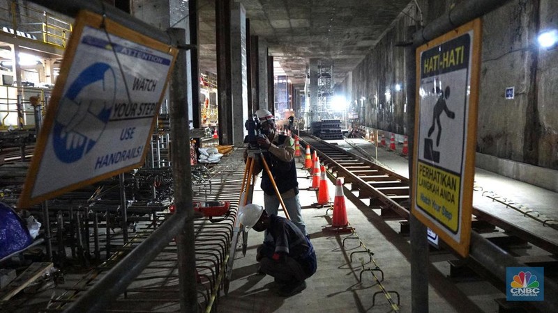 Sejumlah pekerja melintas di samping Tunnel Boring Machine (TBM) atau mesin bor bawah tanah di proyek MRT fase 2A Bundaran HI-Kota di kawasan Glodok, Jakarta, Kamis (11/7/2024). (CNBC Indonesia/Muhammad Sabki)