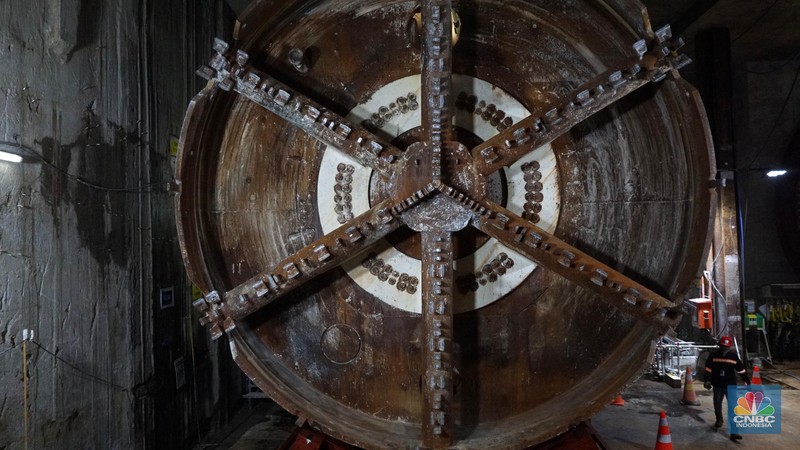 Sejumlah pekerja melintas di samping Tunnel Boring Machine (TBM) atau mesin bor bawah tanah di proyek MRT fase 2A Bundaran HI-Kota di kawasan Glodok, Jakarta, Kamis (11/7/2024). (CNBC Indonesia/Muhammad Sabki)