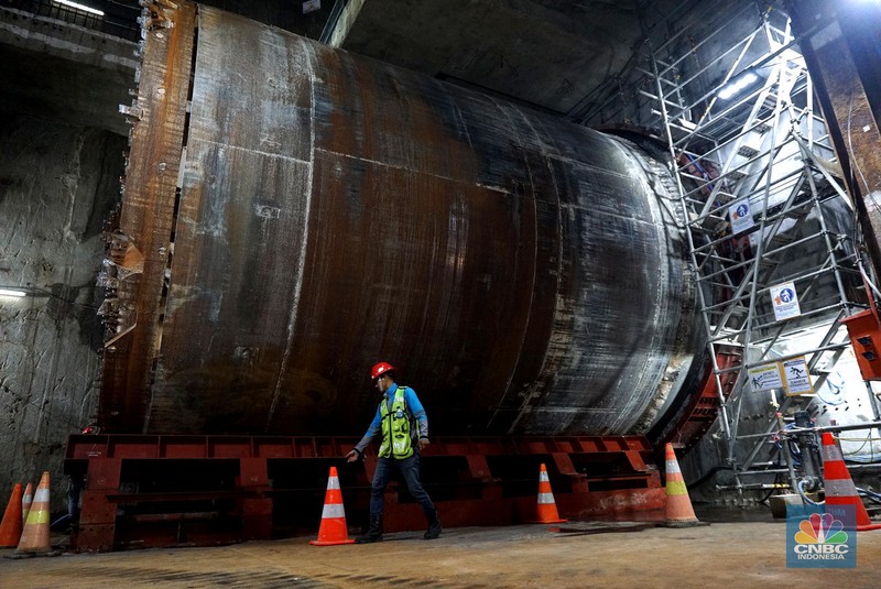 Sejumlah pekerja melintas di samping Tunnel Boring Machine (TBM) atau mesin bor bawah tanah di proyek MRT fase 2A Bundaran HI-Kota di kawasan Glodok, Jakarta, Kamis (11/7/2024). (CNBC Indonesia/Muhammad Sabki)