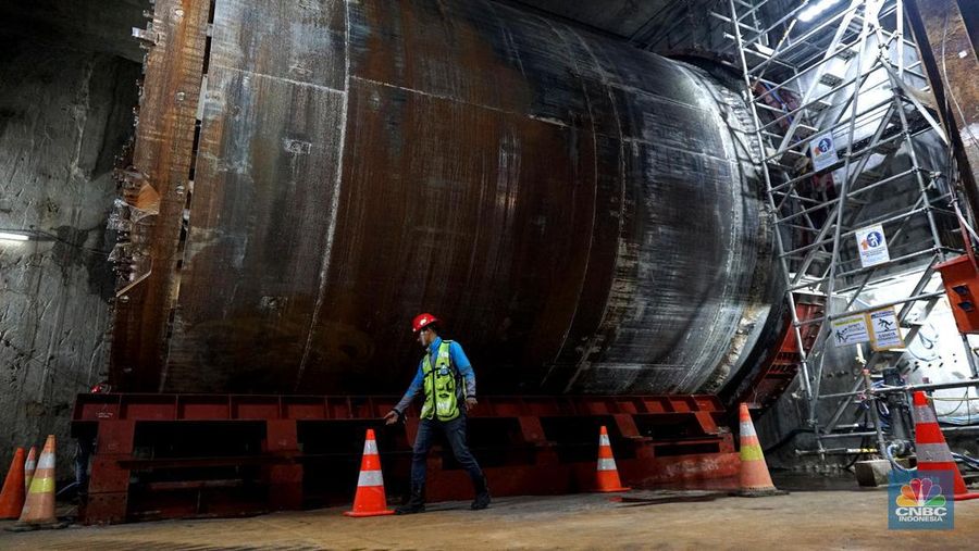Sejumlah pekerja melintas di samping Tunnel Boring Machine (TBM) atau mesin bor bawah tanah di proyek MRT fase 2A Bundaran HI-Kota di kawasan Glodok, Jakarta, Kamis (11/7/2024). (CNBC Indonesia/Muhammad Sabki)