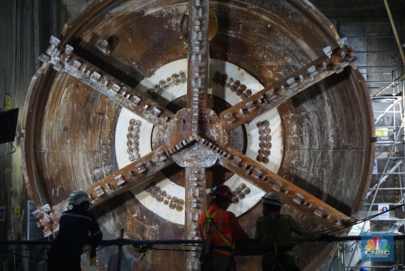 Sejumlah pekerja melintas di samping Tunnel Boring Machine (TBM) atau mesin bor bawah tanah di proyek MRT fase 2A Bundaran HI-Kota di kawasan Glodok, Jakarta, Kamis (11/7/2024). (CNBC Indonesia/Muhammad Sabki)