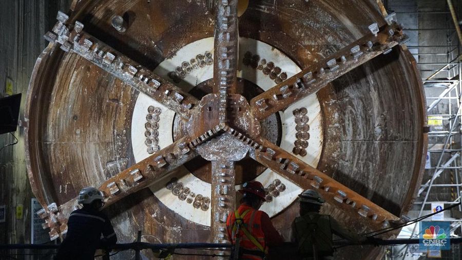 Sejumlah pekerja melintas di samping Tunnel Boring Machine (TBM) atau mesin bor bawah tanah di proyek MRT fase 2A Bundaran HI-Kota di kawasan Glodok, Jakarta, Kamis (11/7/2024). (CNBC Indonesia/Muhammad Sabki)