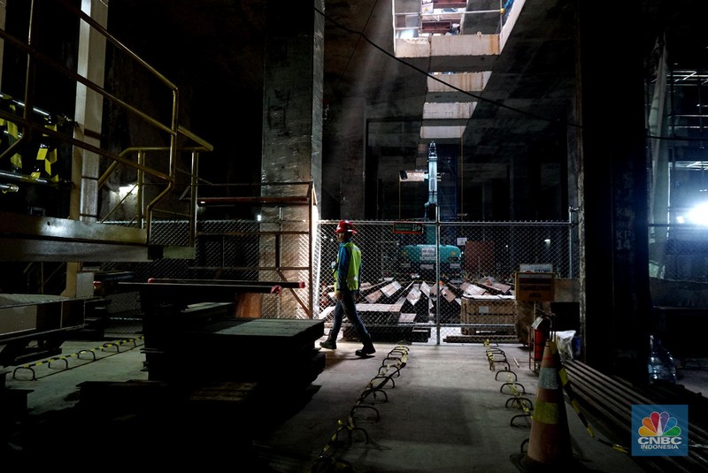 Sejumlah pekerja melintas di samping Tunnel Boring Machine (TBM) atau mesin bor bawah tanah di proyek MRT fase 2A Bundaran HI-Kota di kawasan Glodok, Jakarta, Kamis (11/7/2024). (CNBC Indonesia/Muhammad Sabki)