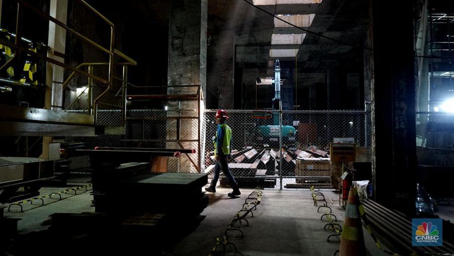 Sejumlah pekerja melintas di samping Tunnel Boring Machine (TBM) atau mesin bor bawah tanah di proyek MRT fase 2A Bundaran HI-Kota di kawasan Glodok, Jakarta, Kamis (11/7/2024). (CNBC Indonesia/Muhammad Sabki)