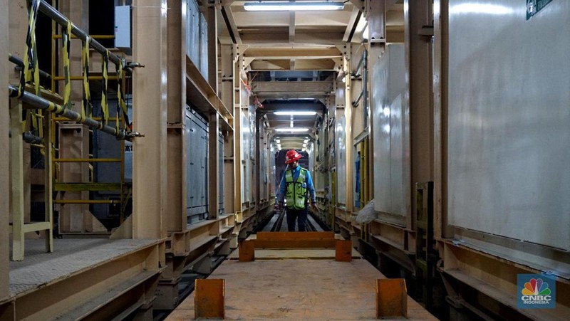 Sejumlah pekerja melintas di samping Tunnel Boring Machine (TBM) atau mesin bor bawah tanah di proyek MRT fase 2A Bundaran HI-Kota di kawasan Glodok, Jakarta, Kamis (11/7/2024). (CNBC Indonesia/Muhammad Sabki)