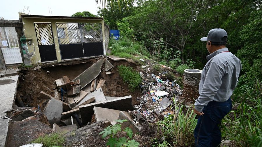 Pria mendorong mobil di jalan yang banjir saat hujan lebat di Veracruz, Meksiko 9 Juli 2024. (REUTERS/Stringer)