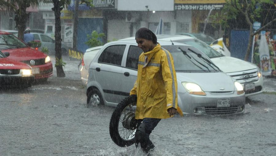 Pria mendorong mobil di jalan yang banjir saat hujan lebat di Veracruz, Meksiko 9 Juli 2024. (REUTERS/Stringer)