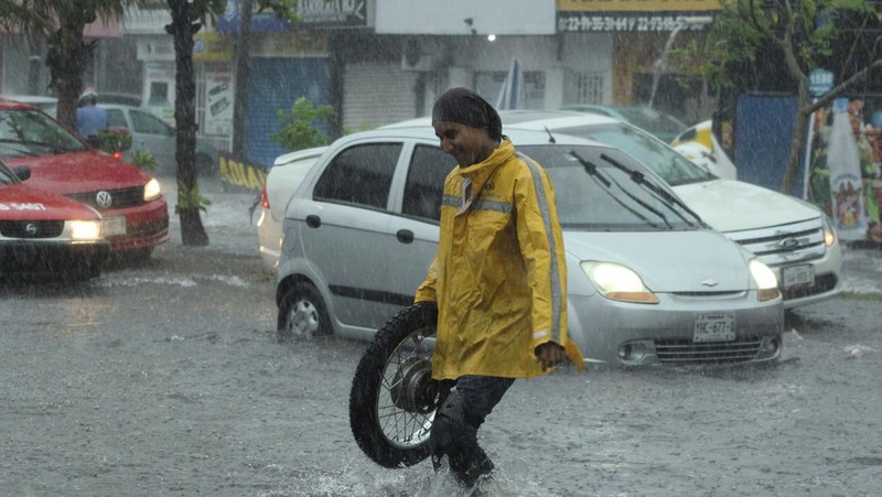 Un automóvil es empujado hacia una carretera inundada durante una fuerte lluvia el 9 de julio de 2024 en Veracruz, México.  (REUTERS/Stringer)