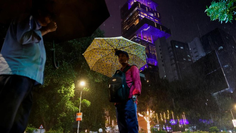 Orang-orang berjalan melewati tempat yang dihiasi lampu menjelang pernikahan putra miliarder Mukesh Ambani, Anant Ambani, dengan Radhika Merchant di Jio World Convention Center di Mumbai, India, Kamis, 11 Juli 2024. (AP Photo/Rafiq Maqbool)