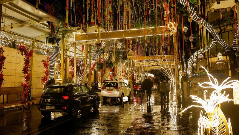 Orang-orang berjalan melewati tempat yang dihiasi lampu menjelang pernikahan putra miliarder Mukesh Ambani, Anant Ambani, dengan Radhika Merchant di Jio World Convention Center di Mumbai, India, Kamis, 11 Juli 2024. (AP Photo/Rafiq Maqbool)
