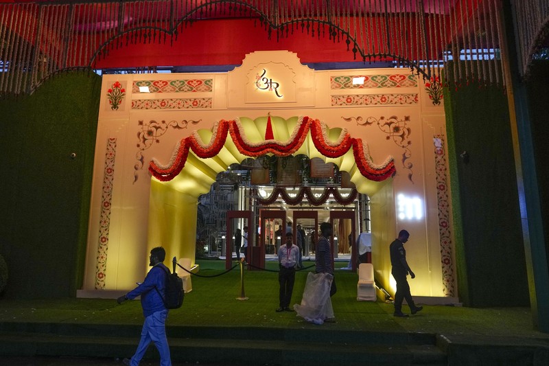 Orang-orang berjalan melewati tempat yang dihiasi lampu menjelang pernikahan putra miliarder Mukesh Ambani, Anant Ambani, dengan Radhika Merchant di Jio World Convention Center di Mumbai, India, Kamis, 11 Juli 2024. (AP Photo/Rafiq Maqbool)