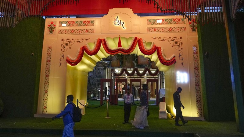 Orang-orang berjalan melewati tempat yang dihiasi lampu menjelang pernikahan putra miliarder Mukesh Ambani, Anant Ambani, dengan Radhika Merchant di Jio World Convention Center di Mumbai, India, Kamis, 11 Juli 2024. (AP Photo/Rafiq Maqbool)
