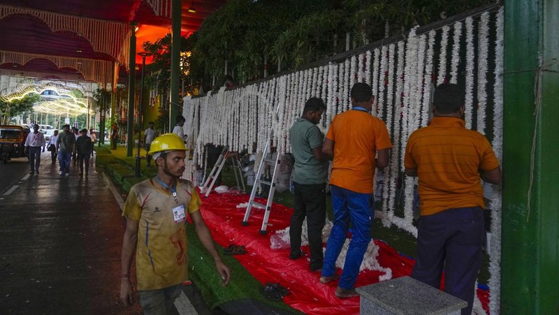 Orang-orang berjalan melewati tempat yang dihiasi lampu menjelang pernikahan putra miliarder Mukesh Ambani, Anant Ambani, dengan Radhika Merchant di Jio World Convention Center di Mumbai, India, Kamis, 11 Juli 2024. (AP Photo/Rafiq Maqbool)